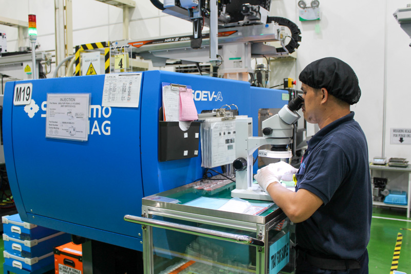 Employee inspecting products in front of an molding machine