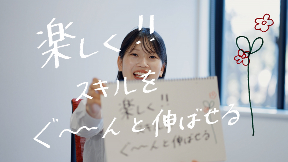 ソフトウェアエンジニアのTさんが「楽しく！　スキルをぐーんと伸ばせる」という言葉とともに笑顔を見せる様子