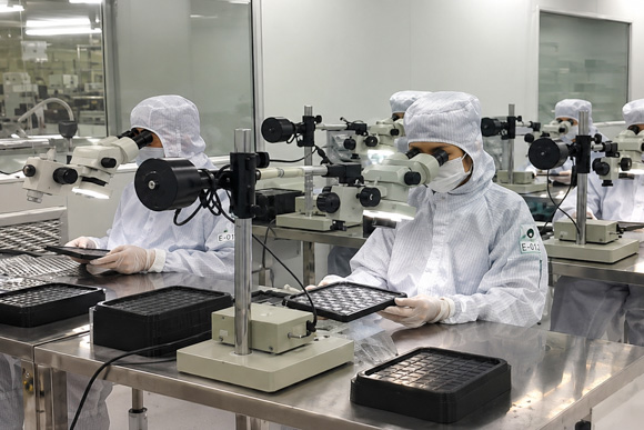 Worker inspecting products with microscopes in a cleanroom
