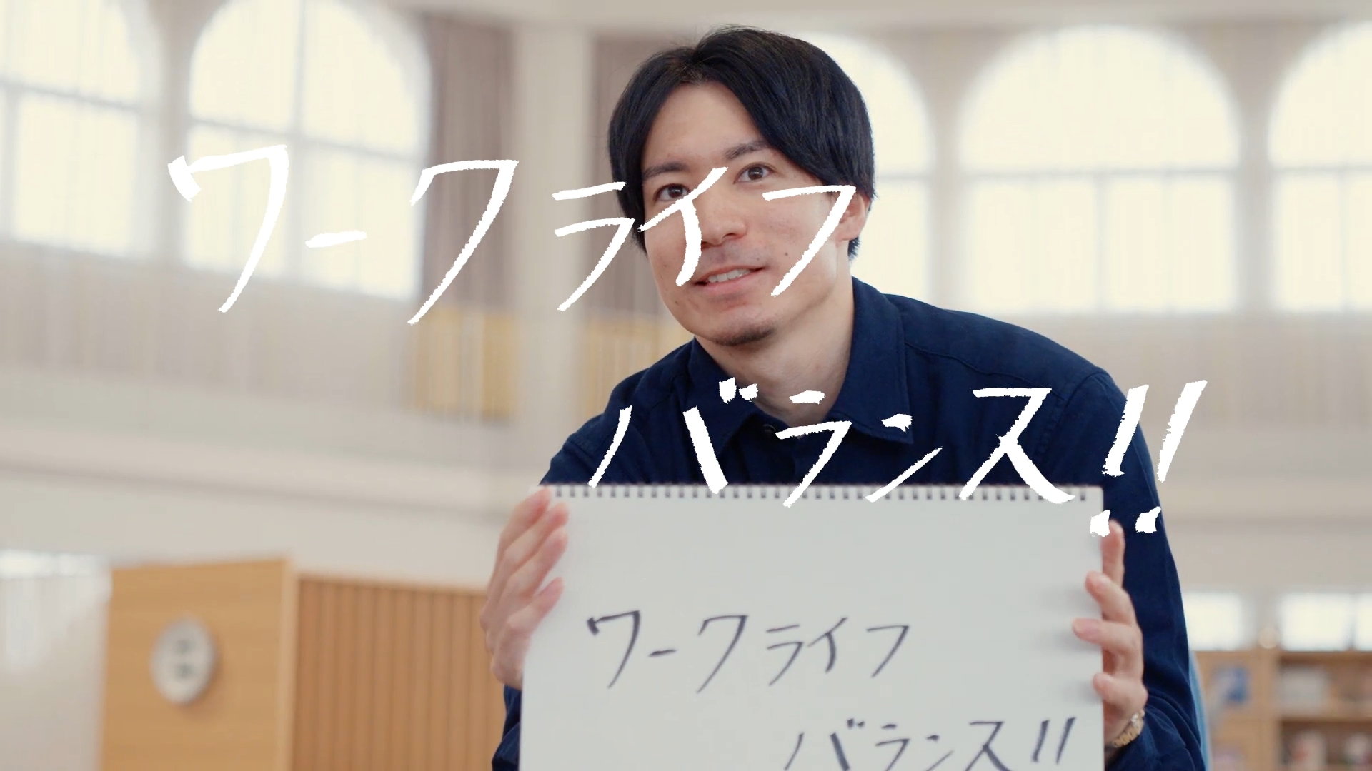 調達のTさんが「ワークライフバランス！！」と書いたスケッチブックを手にしている様子